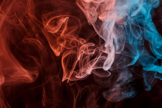 Abstract smoke Weipa. Personal vaporizers fragrant steam. The concept of alternative non-nicotine smoking. Orange blue smoke on a black background. E-cigarette. Evaporator. Taking Close-up. Vaping.