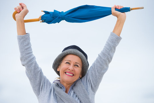 Joyful Mature Woman With Umbrella Arms Up