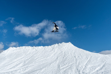 Fototapeta na wymiar Snowboarder jumping against blue sky