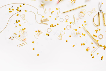 Beauty blog background. Gold style feminine accessories. Golden tinsel, scissors, pen, rings, necklace, bracelet on white background. Flat lay, top view.