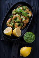 Tiger shrimps with parsley sauce and lemon, black wooden surface
