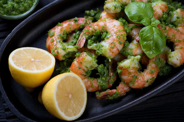 Closeup of tiger shrimps served with chimichurri sauce and lemon