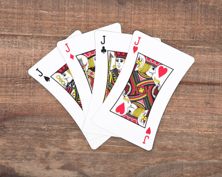 Four poker playing cards on vintage wooden background