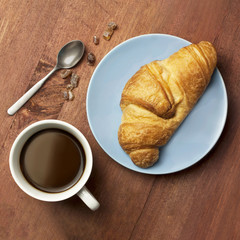 Cup of black coffee with croissant, shot from above