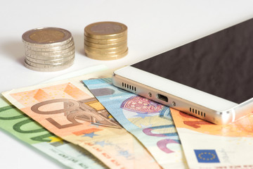 Ein Smartphone und Euro Münzen und Geldscheine