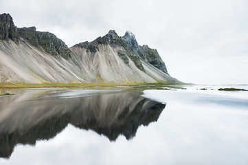 Mountains and reflections on the coast of Atlantic ocean. East Iceland