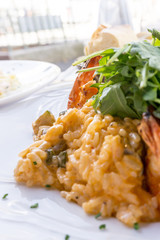 Tasty risotto with Shrimp, fresh herbs vegetables on a white plate