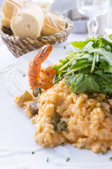 Tasty risotto with Shrimp, fresh herbs vegetables on a white plate