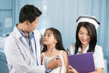 Male doctor examining little asian girl.