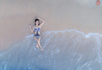 Woman enjoy on the beach at rim of sea edge in aerial view