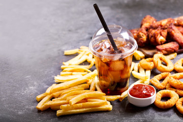 fast food meals : onion rings, french fries, glass of cola and fried chicken