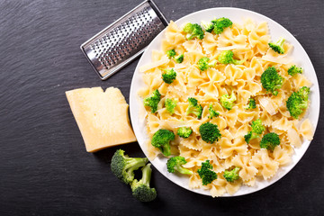 plate of pasta with broccoli and parmesan on dark table
