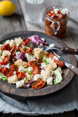 Panzanella salad with roasted tomatoes and feta cheese, closeup view, selective focus