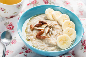 Banana oatmeal porridge with almond nuts and sunflower seeds, closeup view
