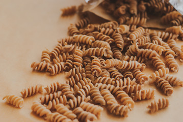 wholemeal pasta fusilli from organic whole grain spelt falling from a paper bag