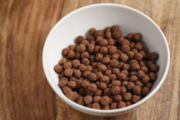 chocolate cereal balls in white bowl for breakfast on wooden table