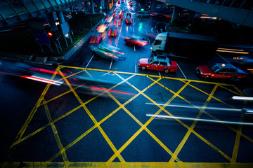 cars driving through yellow no parking area on asphalt street,blue toned,china.