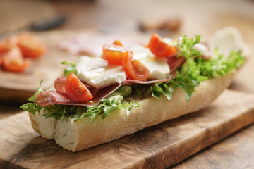 open sandwich with prosciutto, mozzarella and tomatoes on kitchen table