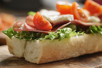 open sandwich with prosciutto, mozzarella and tomatoes on kitchen table