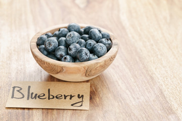 bowl with blueberries with paper card on wood table