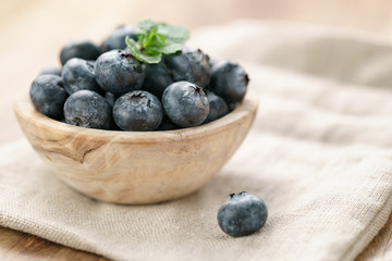 fresh blueberries in bowl on wood table with sack cloth
