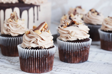 Chocolate cupcake with mousse cream icing on grunge white wooden background copy space