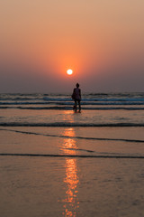 the person against the background of a sunset and the ocean