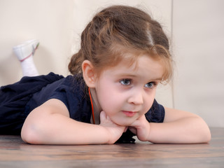 Naklejka premium Portrait of a little girl. The child lies on the floor