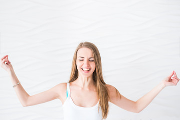 Young smiling girl in white singlet makes meditation on exercise pilates yoga on a white background