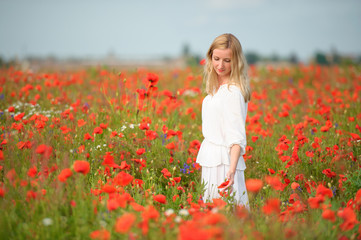 Naklejka na ściany i meble woman in white dress in the blooming poppy field