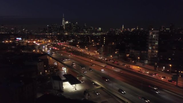 night flying towards New York City skyline alongside elevated highway