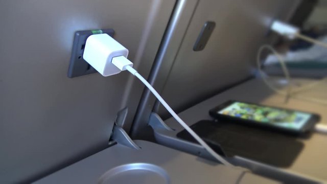 4k Interior airplane, An Old Asian man passenger on a plane using the charger for charge his Smart Phone During Flight-Dan