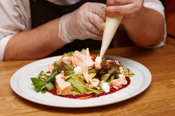 Chef is making appetizer, adding sauce