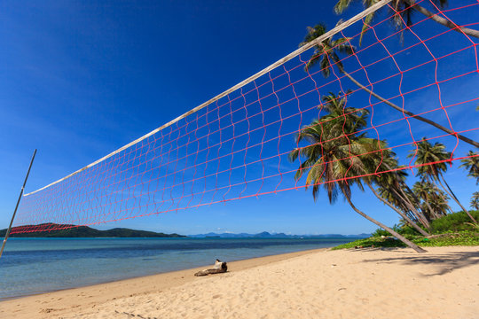 Volleyball net on beach and blue sea with coconut tree.