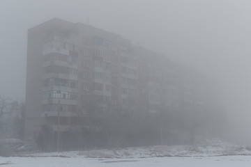 Multi-storey building in the fog. Foggy morning in the winter.