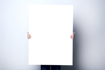Man holding blank poster on grey background
