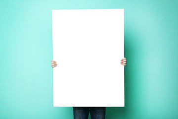 Man holding blank poster on green background