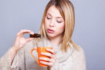 Jeune femme versant de l'huile essentielle dans son mug