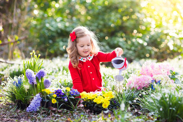 Kids plant and water flowers in spring garden