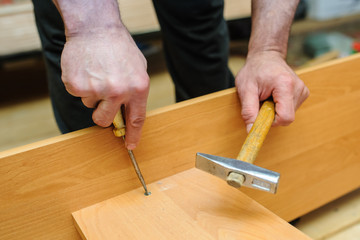 Worker repairing furniture with screwdriver and hammer