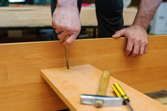 Worker repairing furniture with screwdriver and hammer