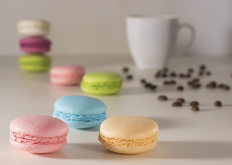 A multicolor french macaroons with cup of coffee on light background