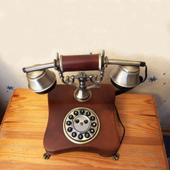 Rare vintage wired phone with round disc for dialing. Apparatus to transmit human speech at distance the telephone wire, made of wood and metal. Ancient technology - harbingers of modern development. 