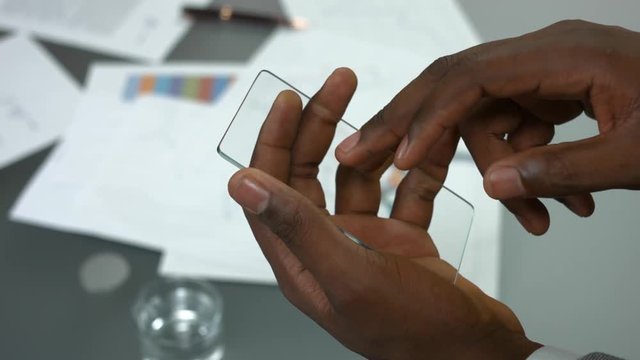 Transparent phone and male hands. Smartphone with blank screen.