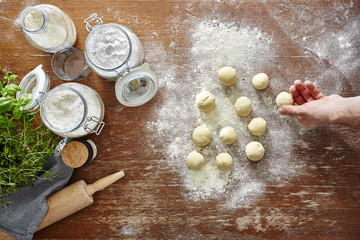 hand rolling out dough little pieces of dough on wooden kitchen workspace