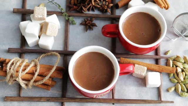 Hot sweet cocoa chocolate drink in cups with spices and suger. Top view. Slow pan.