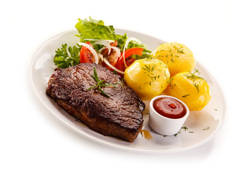 Grilled steaks, boiled potatoes and vegetable salad on white background 