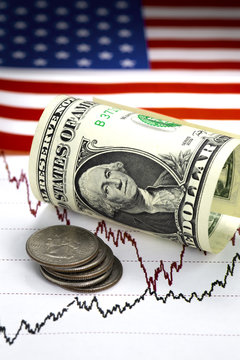 Stock market prices chart. Black and red lines of prices on the chart. Heap of quarter dollar us coins near rolled one us dollar bill. USA flag as a background. Close up image.Stock exchange concept.