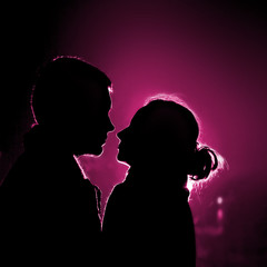 Two lovers in backlight looking each other on date
