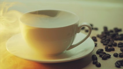 White cup of steaming hot drink on background of coffee beans